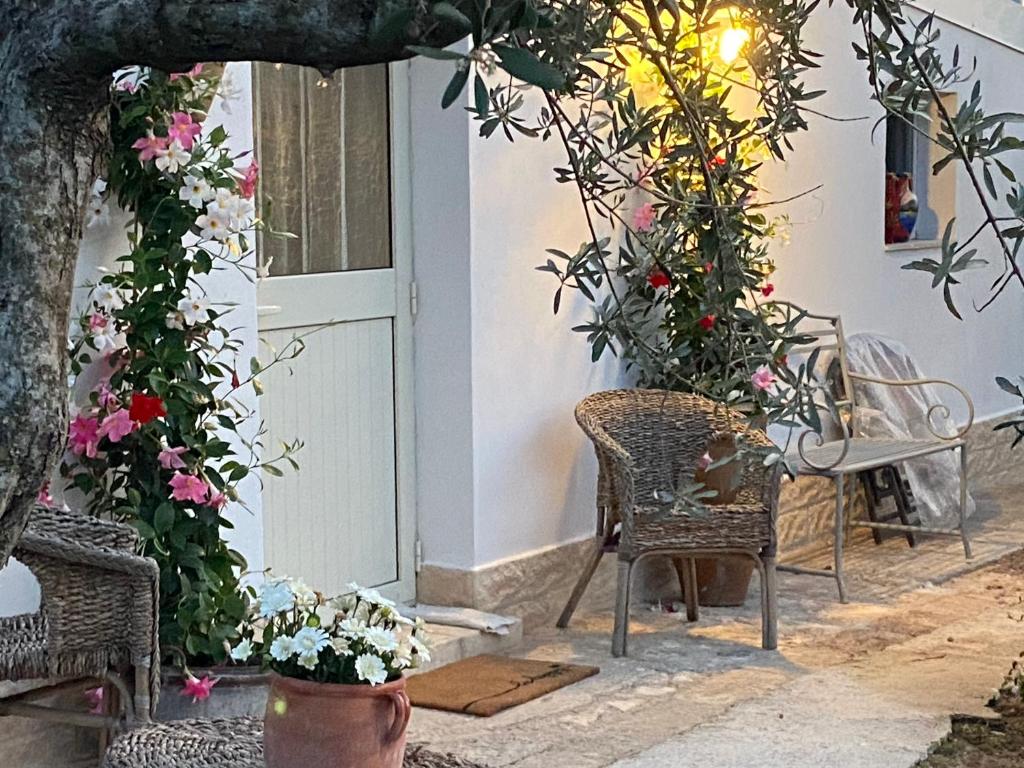 una porta d'ingresso di una casa con fiori e sedie di Rifugio tra gli ulivi a Marina di Ragusa