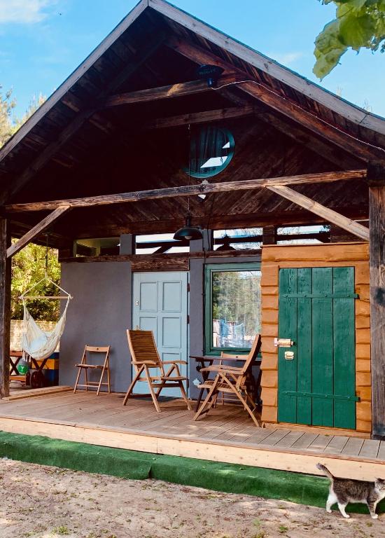 a cabin with a green door and chairs on a deck at Leśny Zakątek agroturystyka z głaskaniem zwierząt in Ożarów