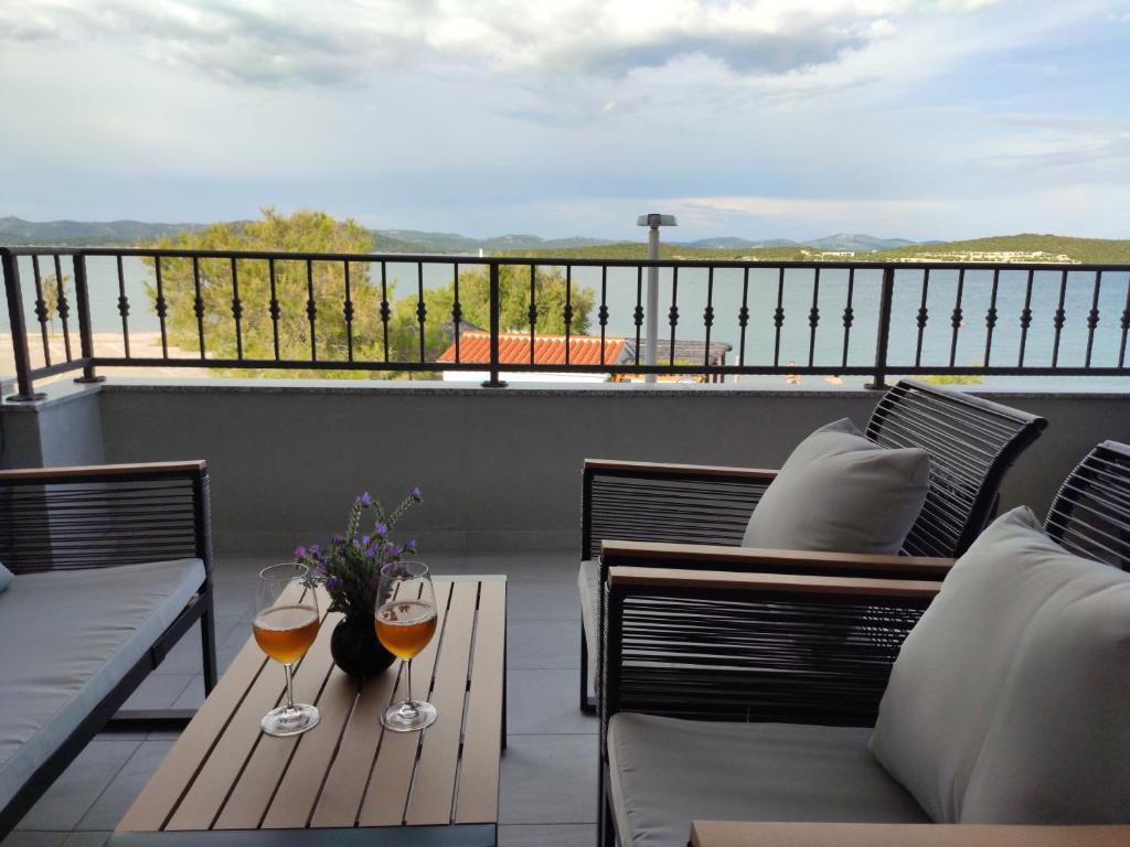 un patio con 2 copas de vino en un balcón en Apartmani Šara 2, en Betina