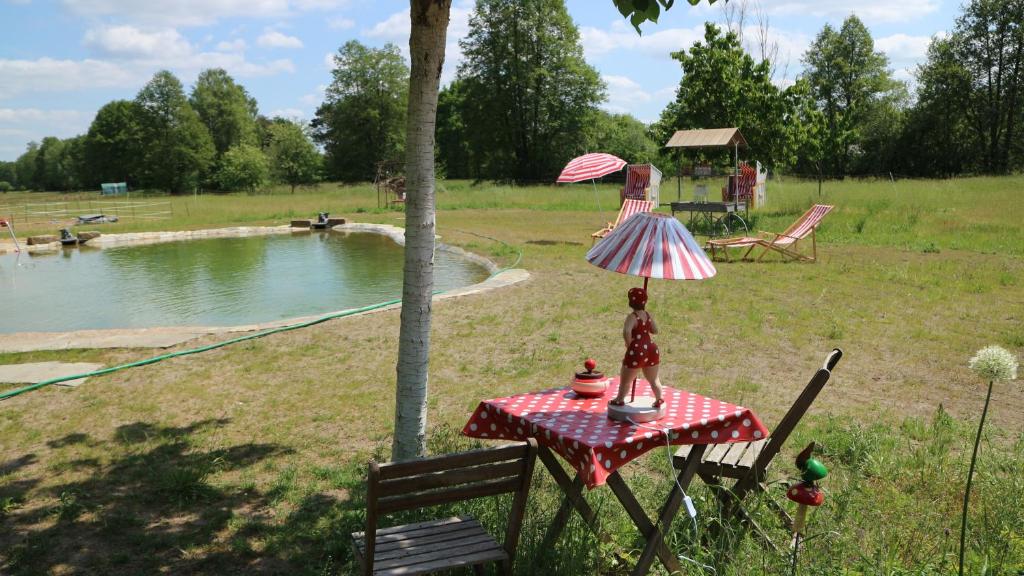 a doll on a table with an umbrella next to a pond at Ferienhof "Zum Spreewäldchen" in Burg