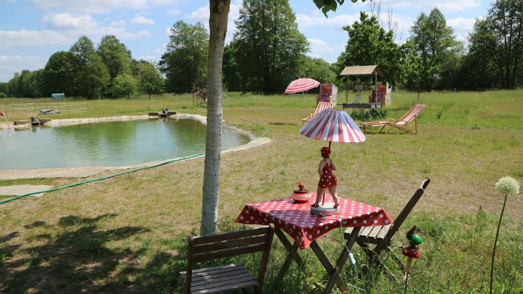 eine Puppe auf einem Tisch mit einem Regenschirm neben einem Teich in der Unterkunft Ferienhof "Zum Spreewäldchen" in Burg
