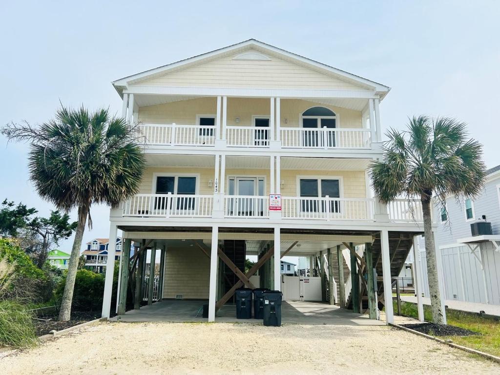 a large white house with palm trees in front of it at Salt, Sand and Sudds home in Holden Beach
