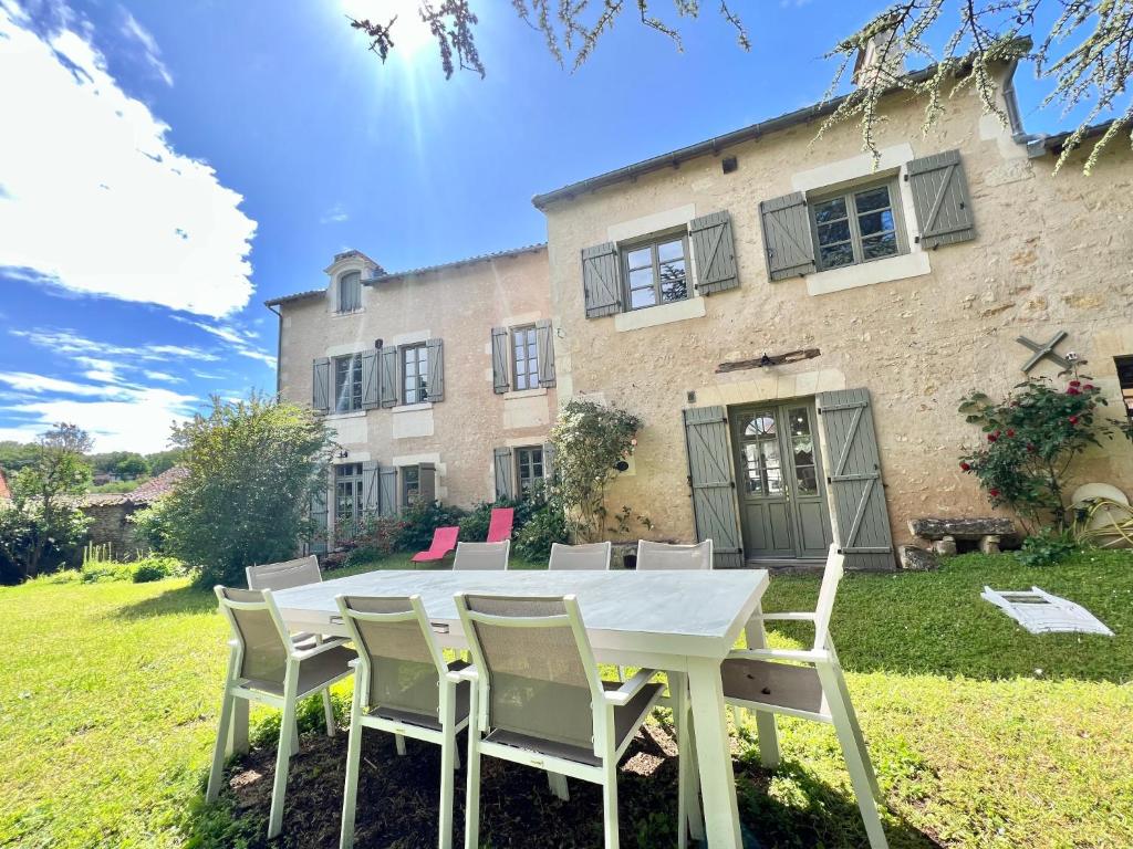 une table et des chaises blanches devant un bâtiment dans l'établissement Au Domaine Valigny, piscine chauffée + WIFI Fibre, à Saint-Benoît