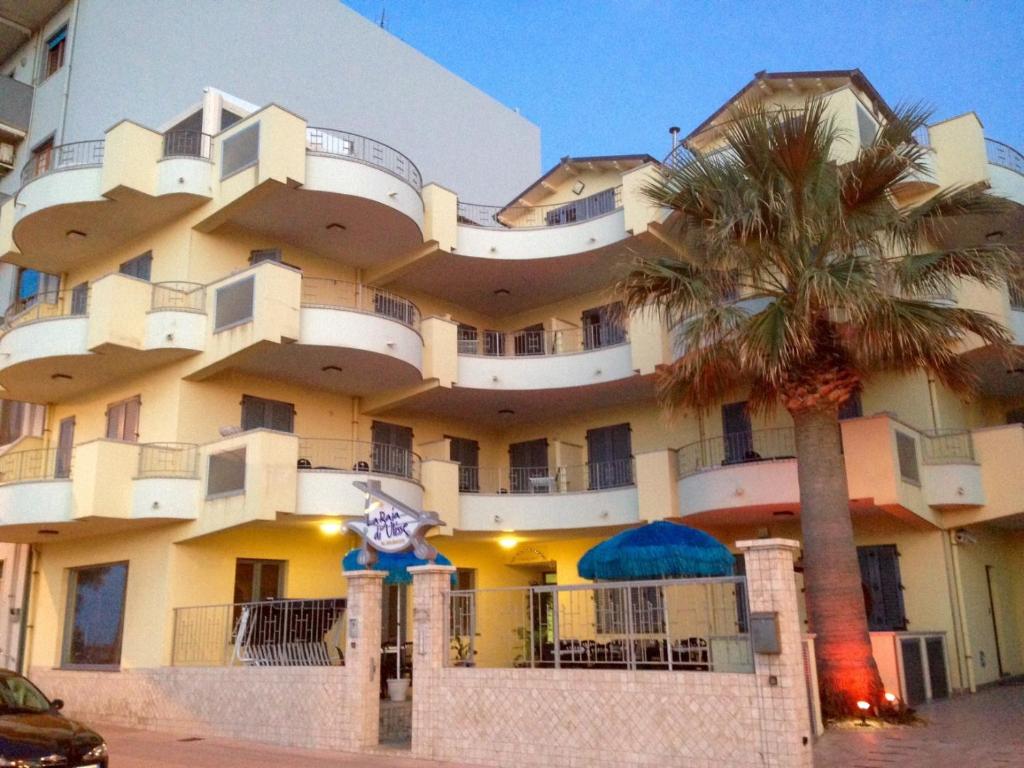 a large building with a palm tree in front of it at La Baia Di Ulisse in Venetico