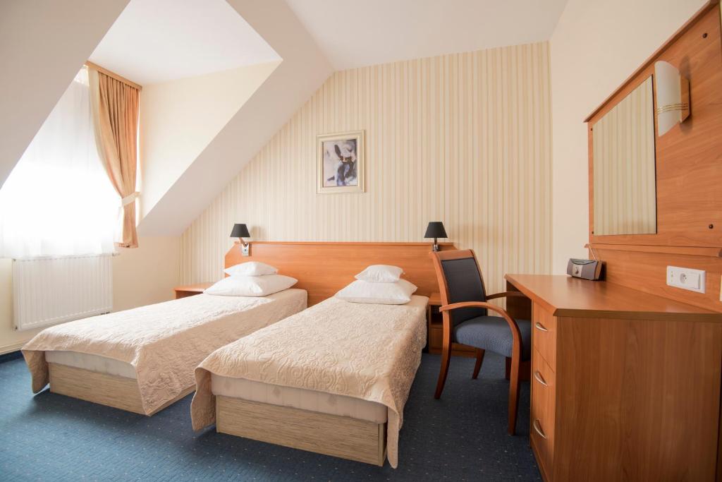 a hotel room with two beds and a desk at Hotel Daria in Tychy