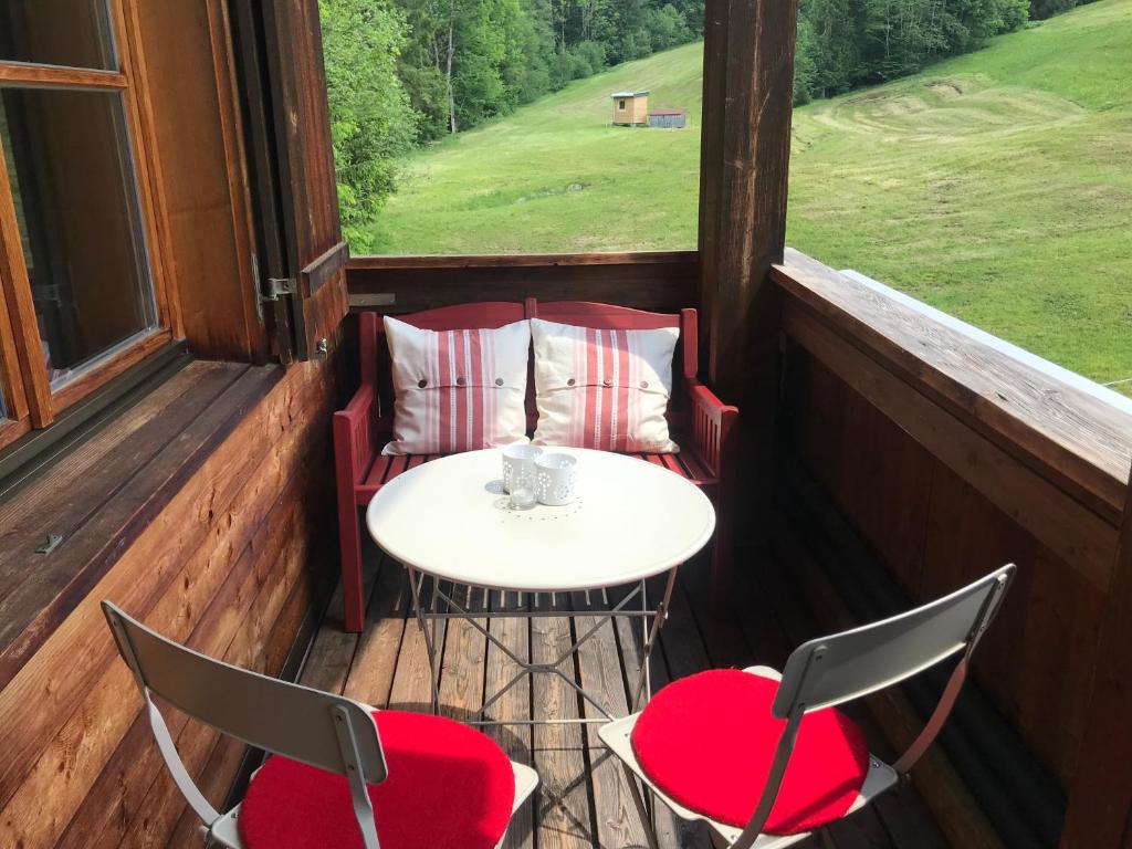 einen Tisch und Stühle auf einer Veranda mit einem Tisch und 2 Stühlen in der Unterkunft Ferienwohnung Morgentau am Rande der Wildnis in Sibratsgfäll