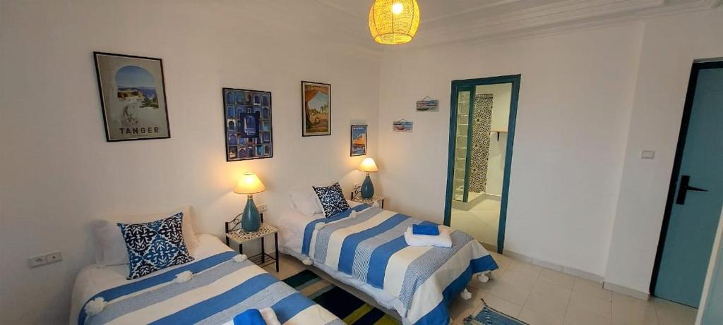 Habitación con 2 camas y 2 lámparas en la pared. en CASA ZOUINA, en Agadir