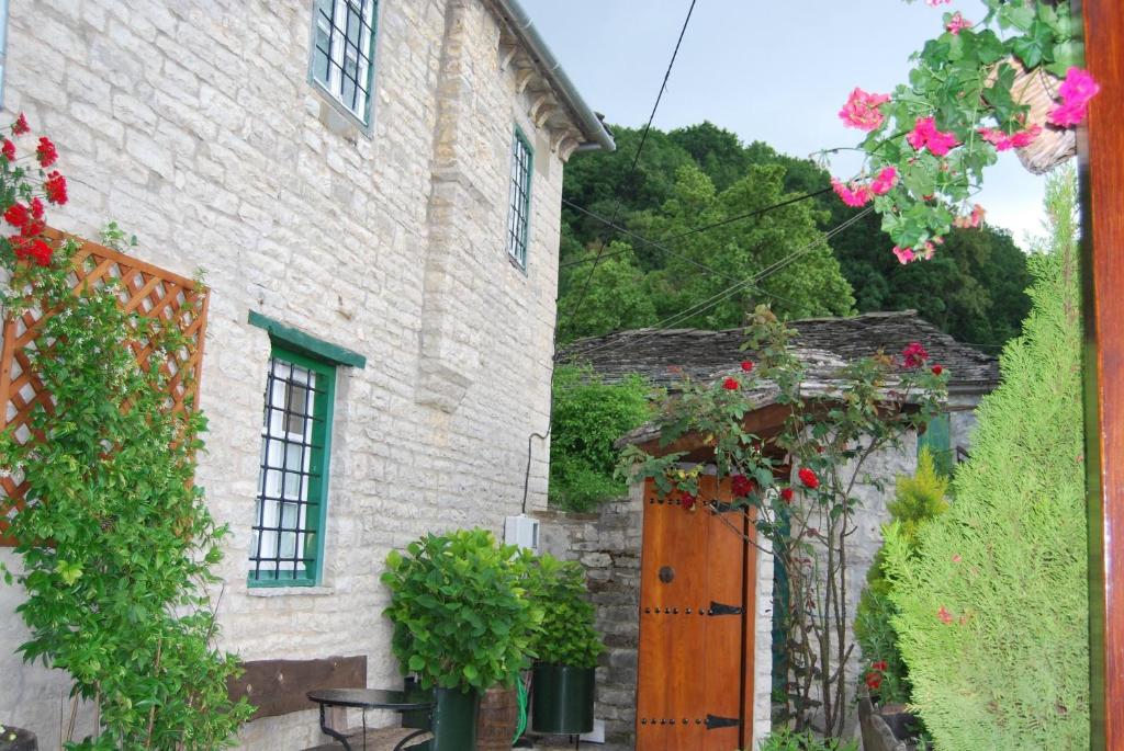 an old stone house with a wooden door and flowers at Tritoxo Guesthouse in Koukouli