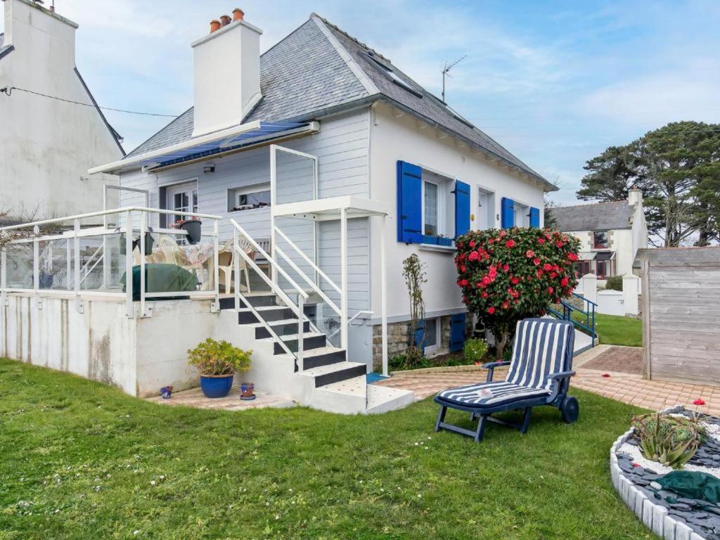 a white house with blue windows and a chair in the yard at La Glycine in Lampaul-Plouarzel