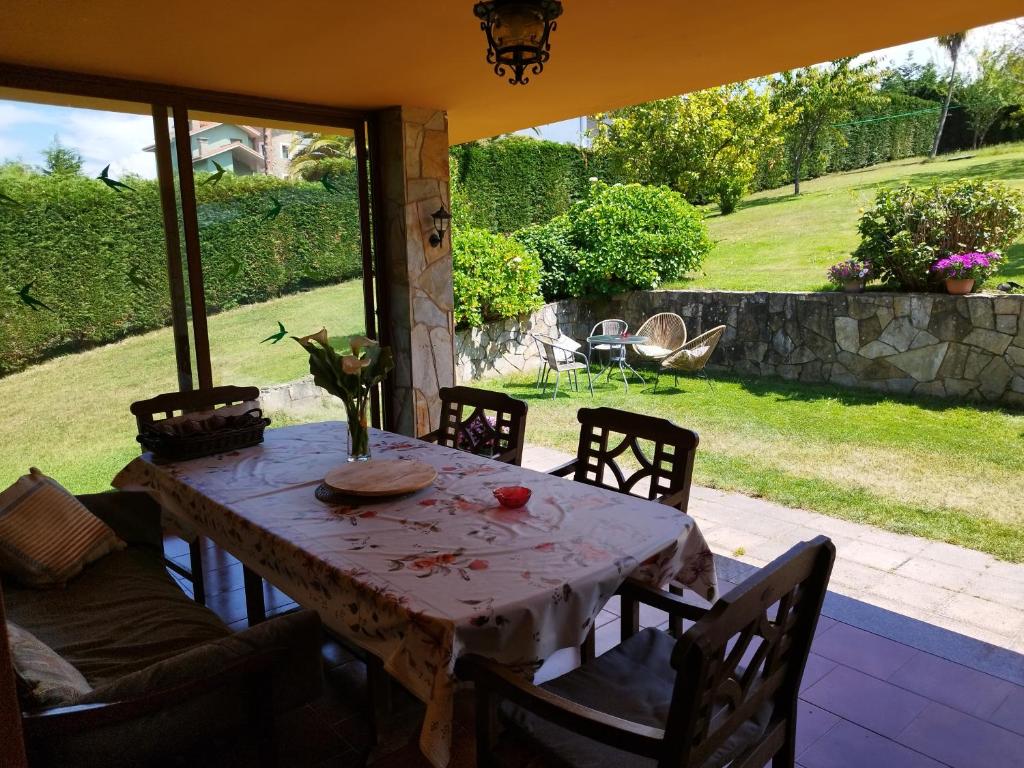 a table and chairs on a patio with a view of a yard at PISCINA CLIMATIZADA - todo el año- Playa de la Ñora-chimenea- barbacoa in Quintueles