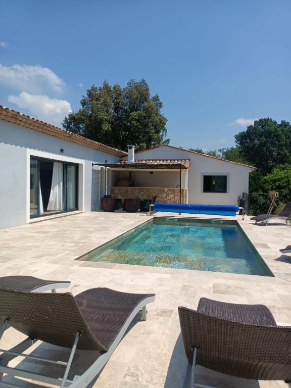 une piscine avec des chaises et une maison dans l'établissement Villa au calme, à Montauroux