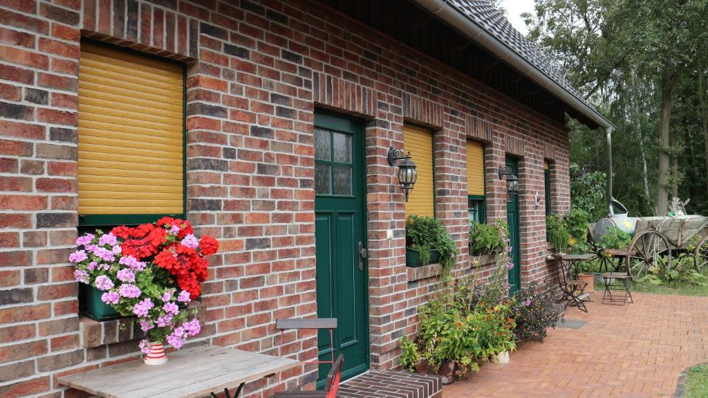ein Backsteingebäude mit einer grünen Tür und einer Bank mit Blumen in der Unterkunft Ferienhof "Zum Spreewäldchen" in Burg
