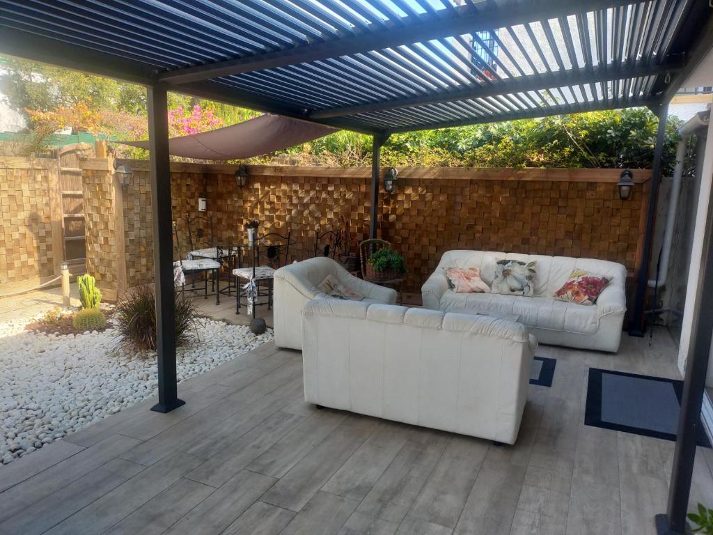 un patio con 2 sofás blancos bajo una pérgola en Bonita casa adosada en esquina, en Marbella