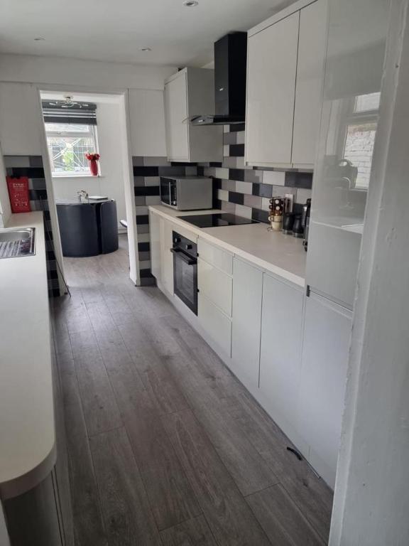 a kitchen with white cabinets and a wooden floor at Margate Town House in Kent