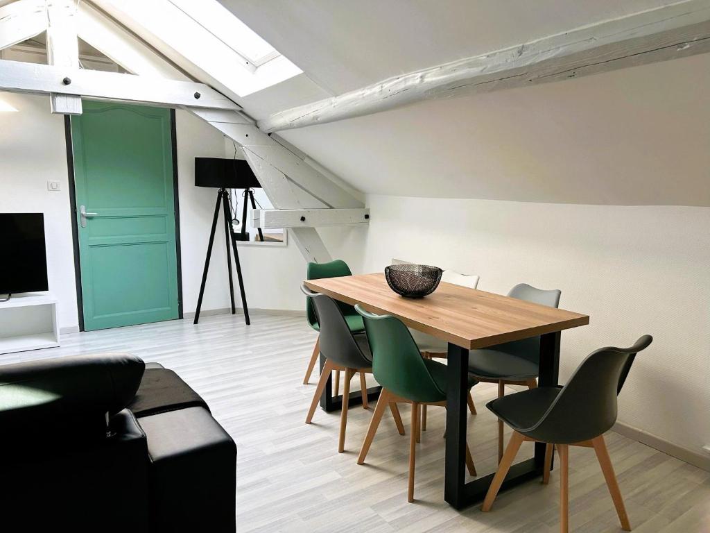 a dining room with a wooden table and green chairs at Appartement climatisé Le Gambetta in Pont-à-Mousson