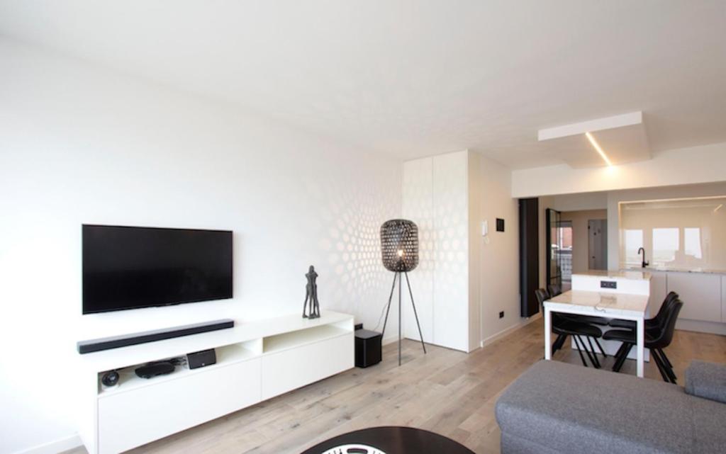 ein Wohnzimmer mit einem TV an einer weißen Wand in der Unterkunft Riva Bella 1.01 in Nieuwpoort