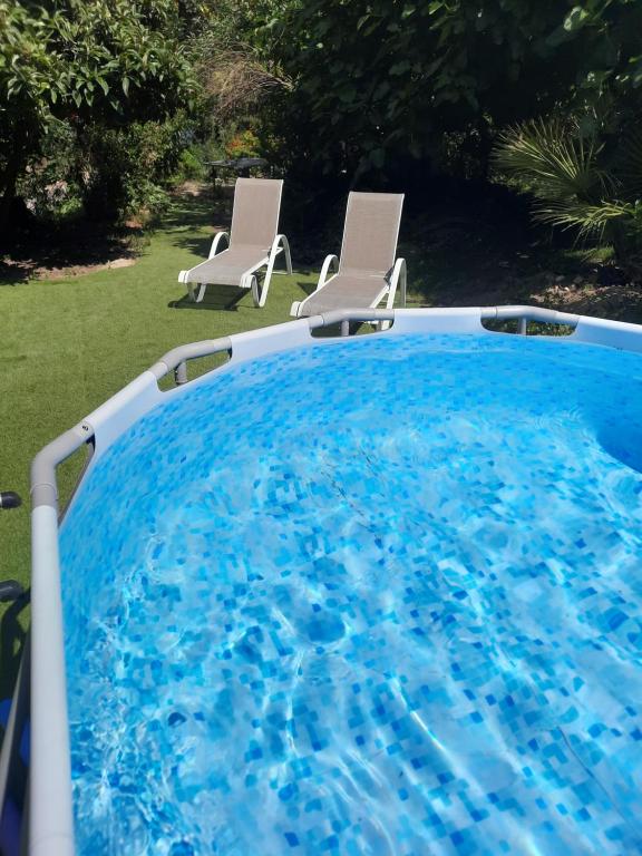 una gran piscina azul con 2 sillas en un patio en La Palmeraie, en Istres