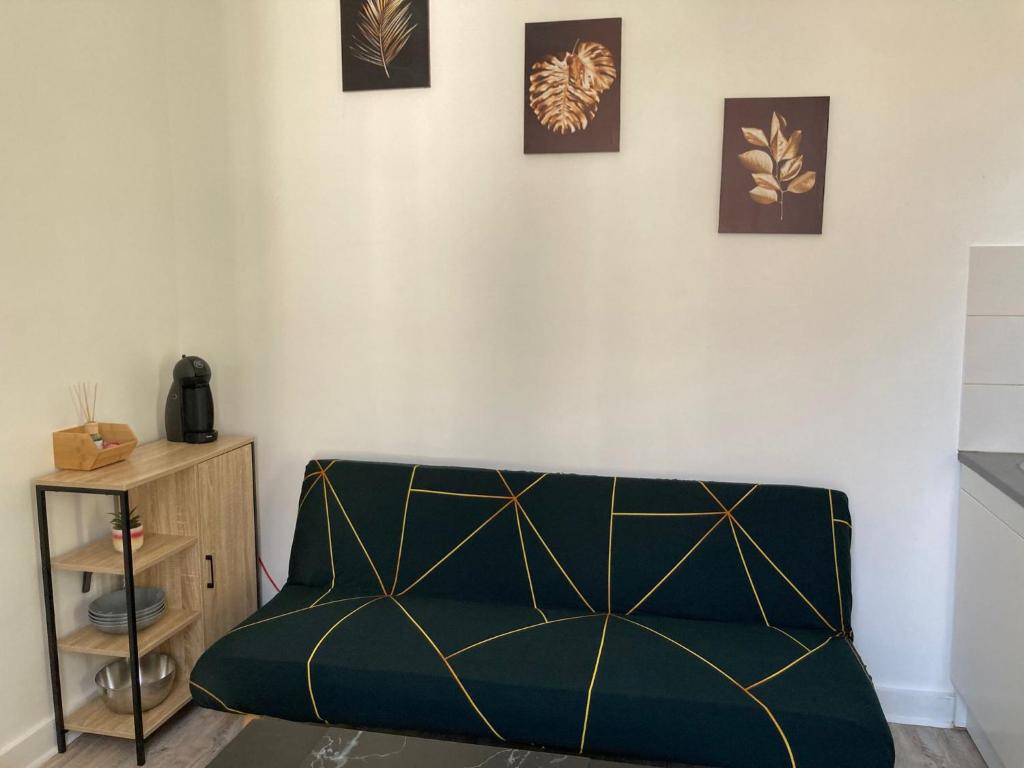 un sofá verde en una habitación con tres cuadros en la pared en Appartements Saint Gratien 3 min à pied transport Tour Eiffel, en Saint-Gratien