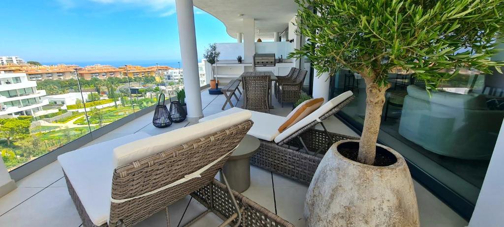 een balkon met een tafel en stoelen en een boom bij Mara's Apartments Higueron West - Scandinavian Luxury - Views of the Sea and Natural Landscapes in Fuengirola