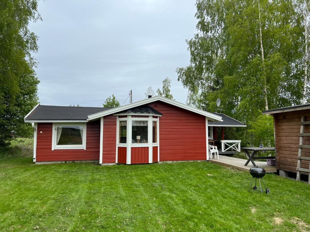 a red house with a yard with a grill at Cottage Stranden in Kruunupyy