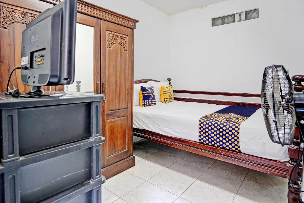 ein Schlafzimmer mit einem Bett und einem TV auf einer Kommode in der Unterkunft SPOT ON 92595 Umi Homestay Syariah in Sidoarjo