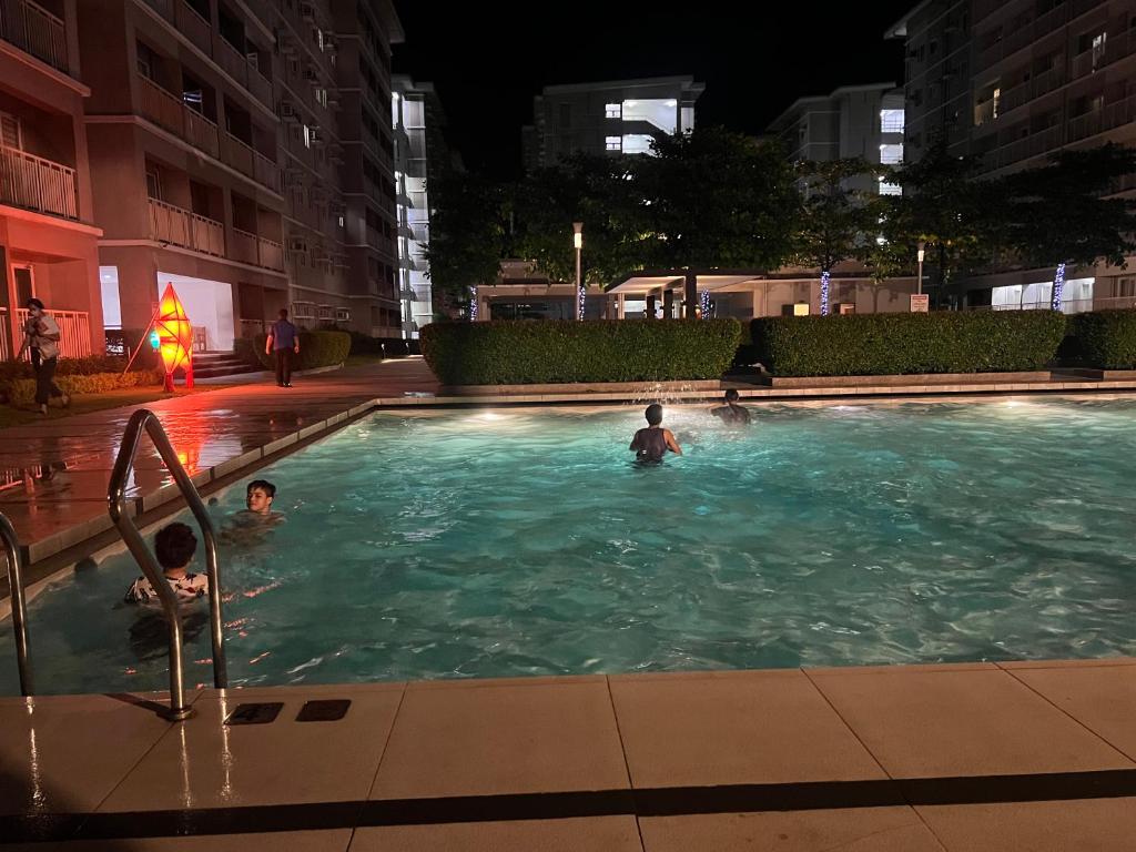 3 Personen schwimmen nachts im Pool in der Unterkunft MISR Suite QC in Manila