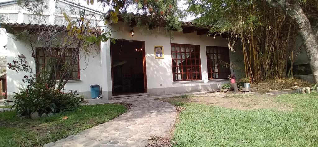 a white house with a tree in front of it at Casa de descanso familiar Panajachel in Panajachel