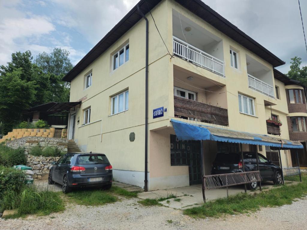 a house with two cars parked in front of it at Rooms Mery in Visoko