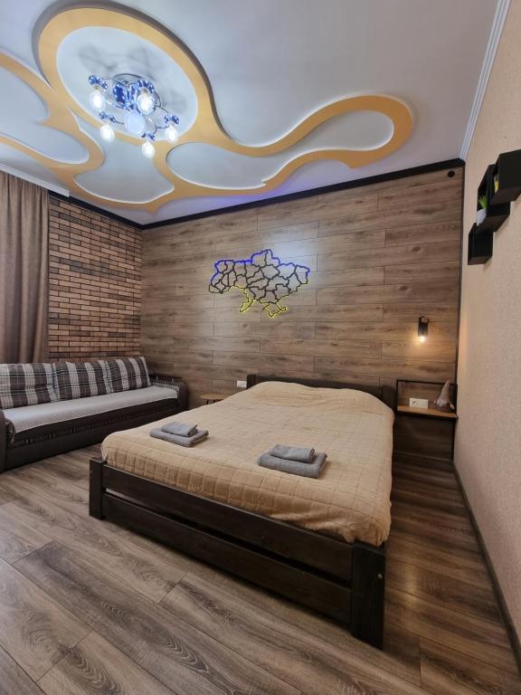 ein Schlafzimmer mit einem Bett, einem Sofa und einer Decke in der Unterkunft Petropavlivska apartment in Kamjanez-Podilskyj