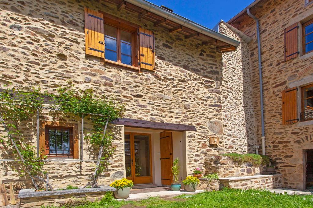 una casa in pietra con finestre in legno e una porta di Gîte les Tilleuls ad Arlanc