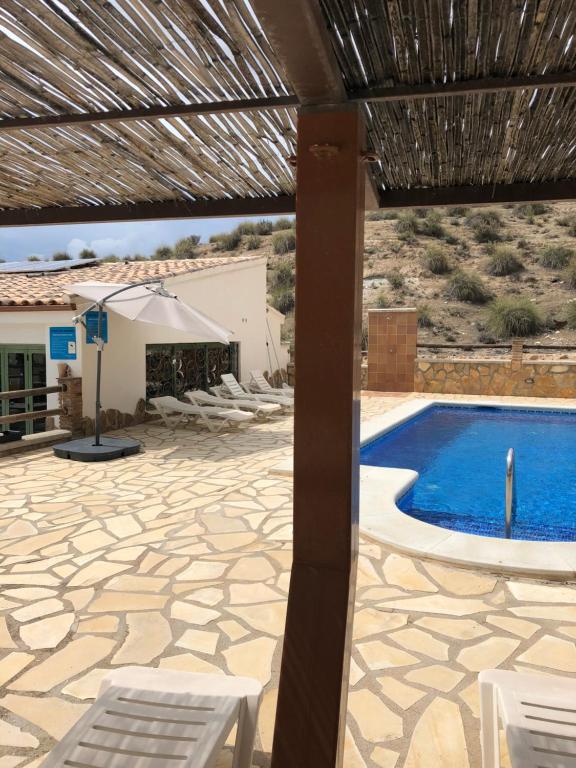 eine Terrasse mit einem Pool und Stühlen sowie ein Gebäude in der Unterkunft Alojamiento Cuevas Victoria in Galera