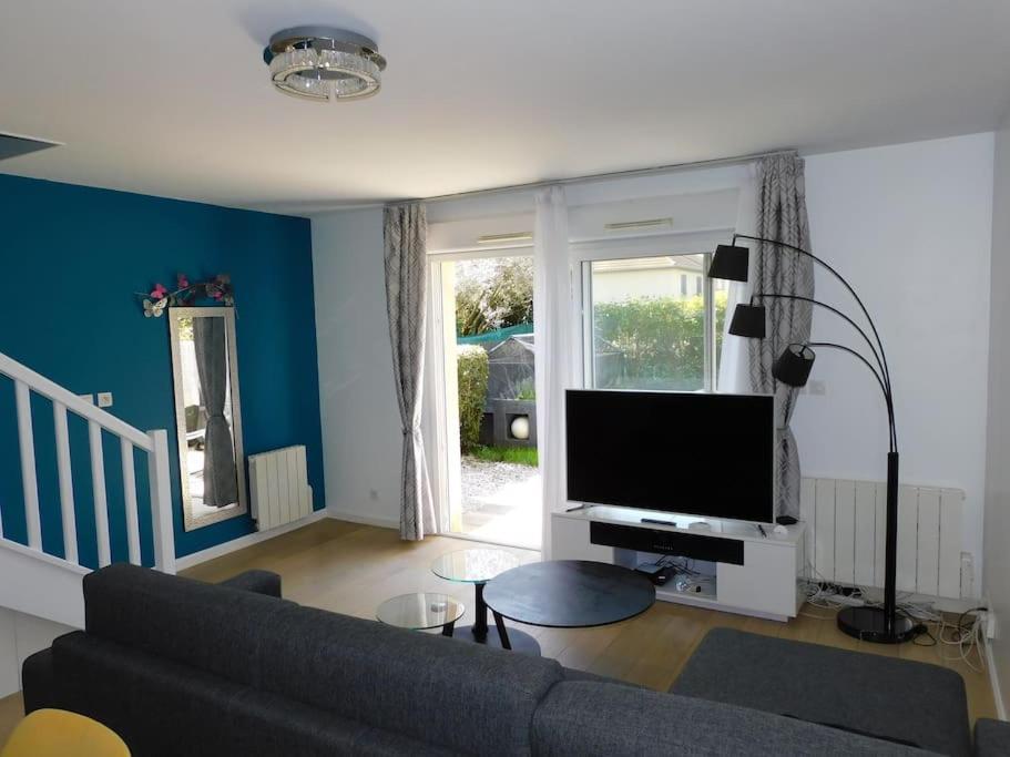 un salon avec un canapé et une télévision à écran plat dans l'établissement Maison Mitoyenne (Duplex), à Prévessin-Moëns