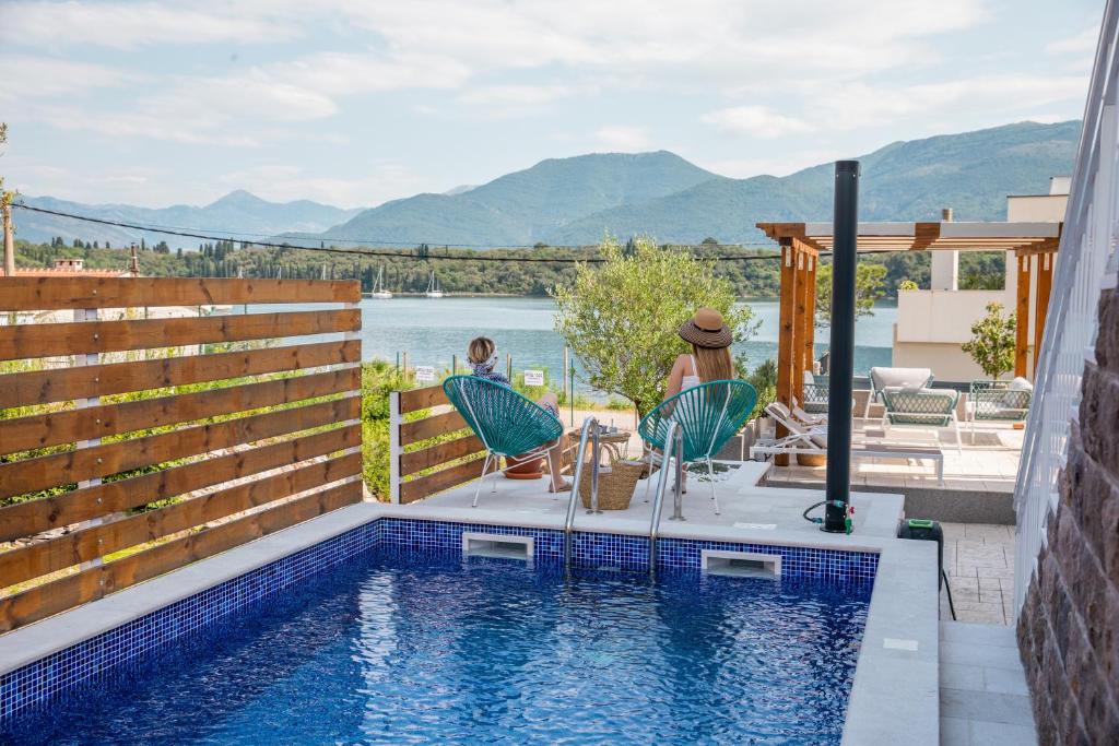 una piscina con dos personas sentadas en sillas junto a una casa en Villa Gioia en Tivat