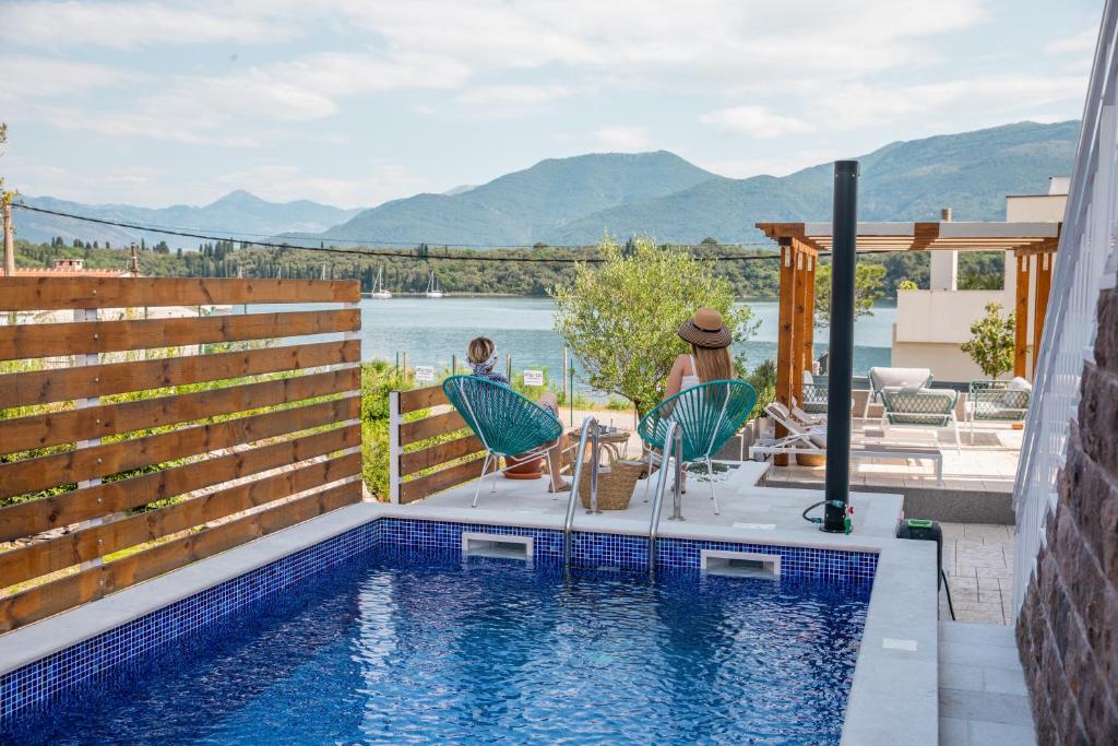 a pool with two people sitting in chairs next to a house at Villa Gioia in Tivat