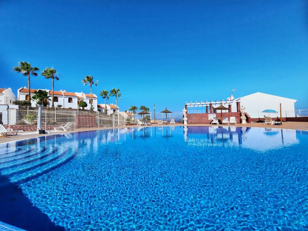 a large swimming pool with blue water and palm trees at Ocean View Villas Canarias in Adeje