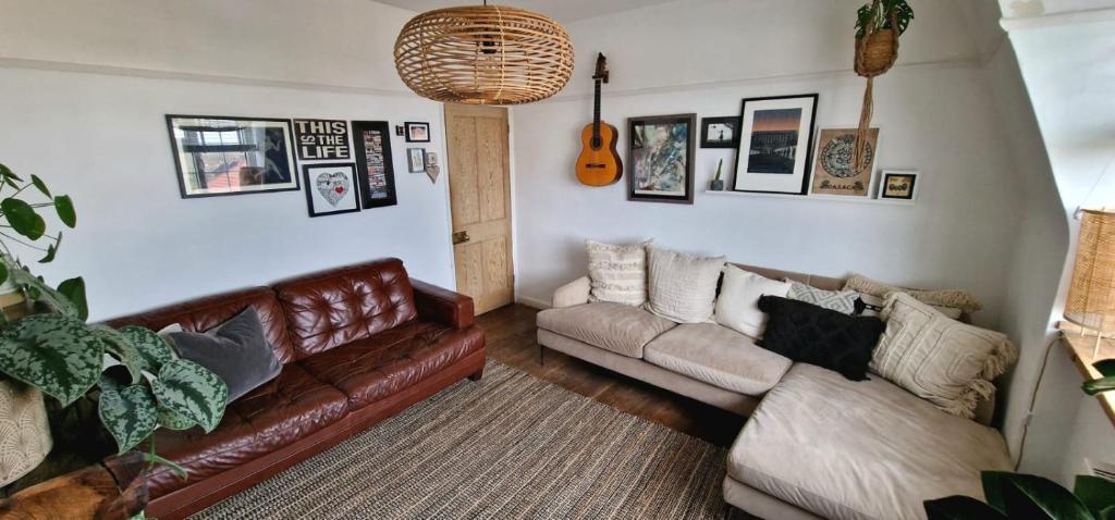 een woonkamer met een bruine leren bank en een gitaar bij Bright Cosy 1 Bed Apartment, SE London in Chislehurst