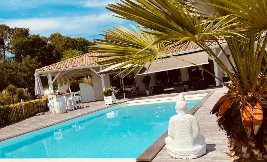 une statue de buddha assise à côté d'une piscine dans l'établissement Calme et détente à 4 km de l’ocean, à Saint-Julien-en-Born