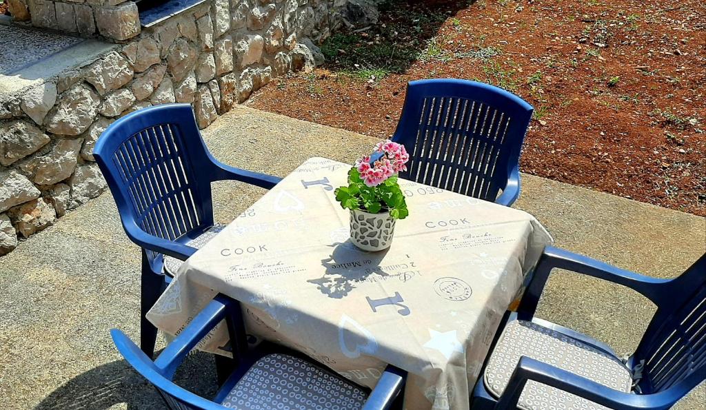 a table with two chairs and a vase with flowers on it at Apartment RB in Omišalj