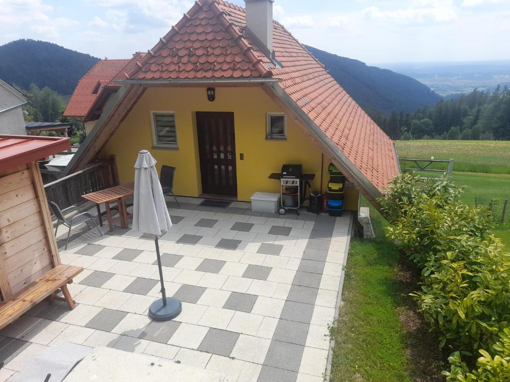 a yellow house with a table and a umbrella at Ferienwohnung Zetzhirsch in Weiz
