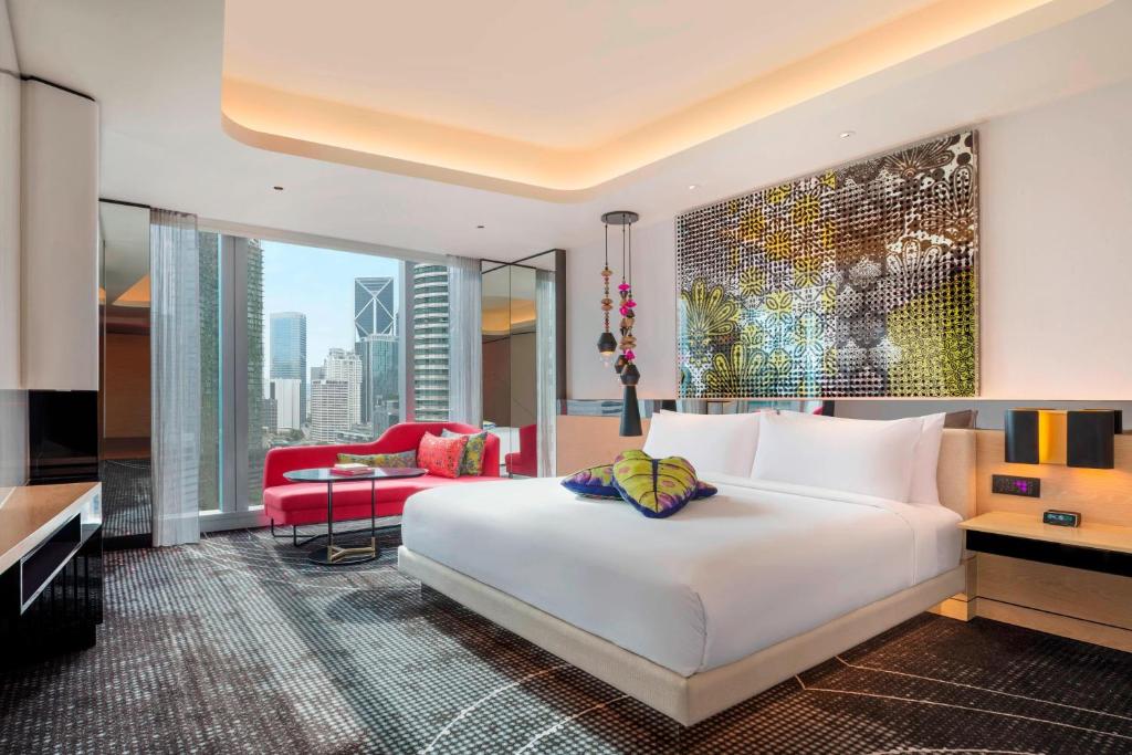 a bedroom with a large white bed and a living room at W Kuala Lumpur Hotel in Kuala Lumpur