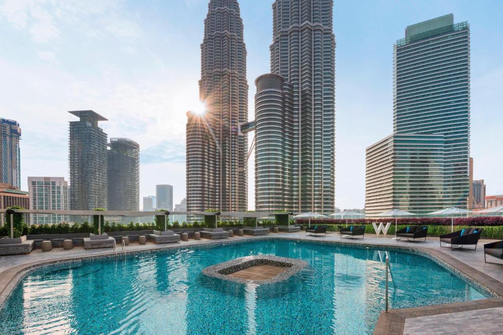 クアラルンプールにあるW Kuala Lumpur Hotelの高層ビルが立ち並ぶ街の中にあるスイミングプール