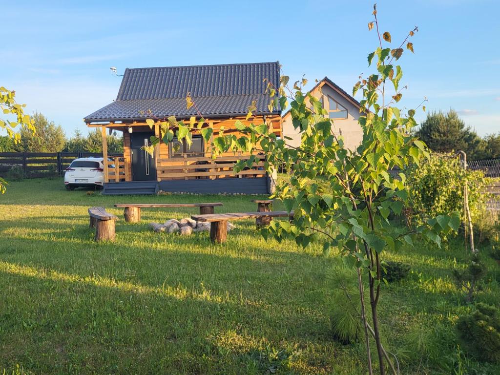 una casa en un campo con un patio con un banco en Przytulny domek w Brajnikach 86 37, en Jedwabno