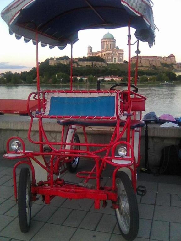 a red cart with an umbrella on the side of a river at Chat in Štúrovo