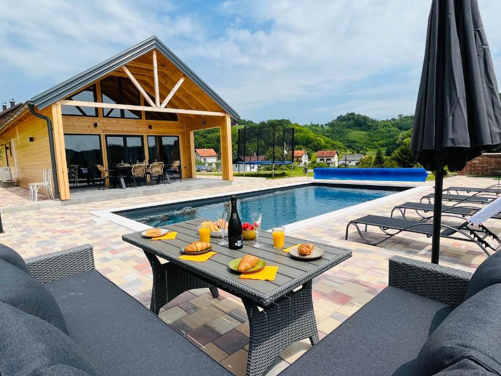 a patio with a table and an umbrella and a pool at Holiday House Novus in Selno