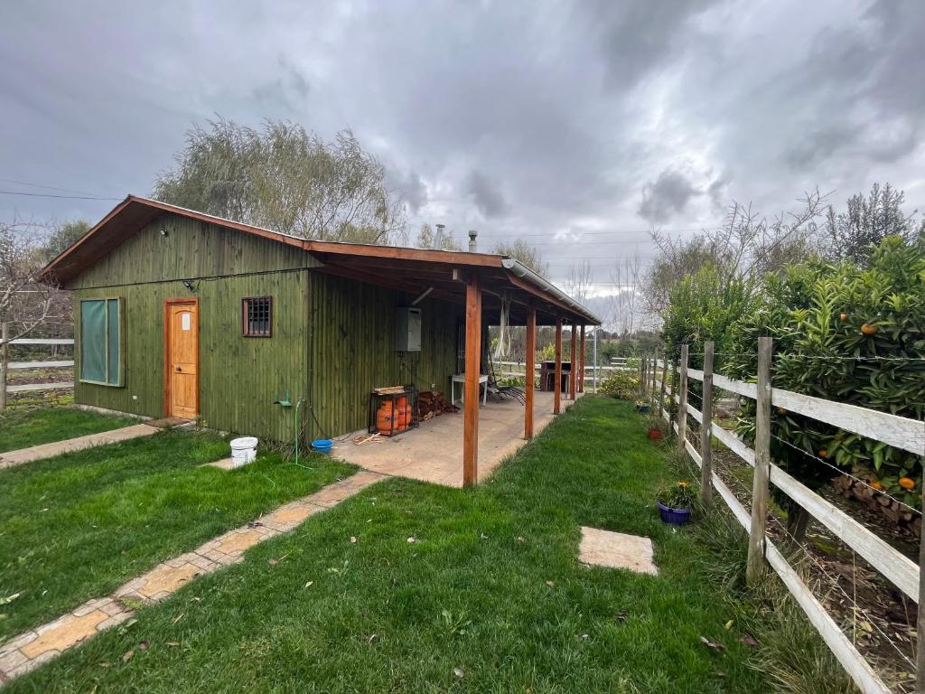 a green shed with a porch and a fence at Alojamiento Machicura in Linares