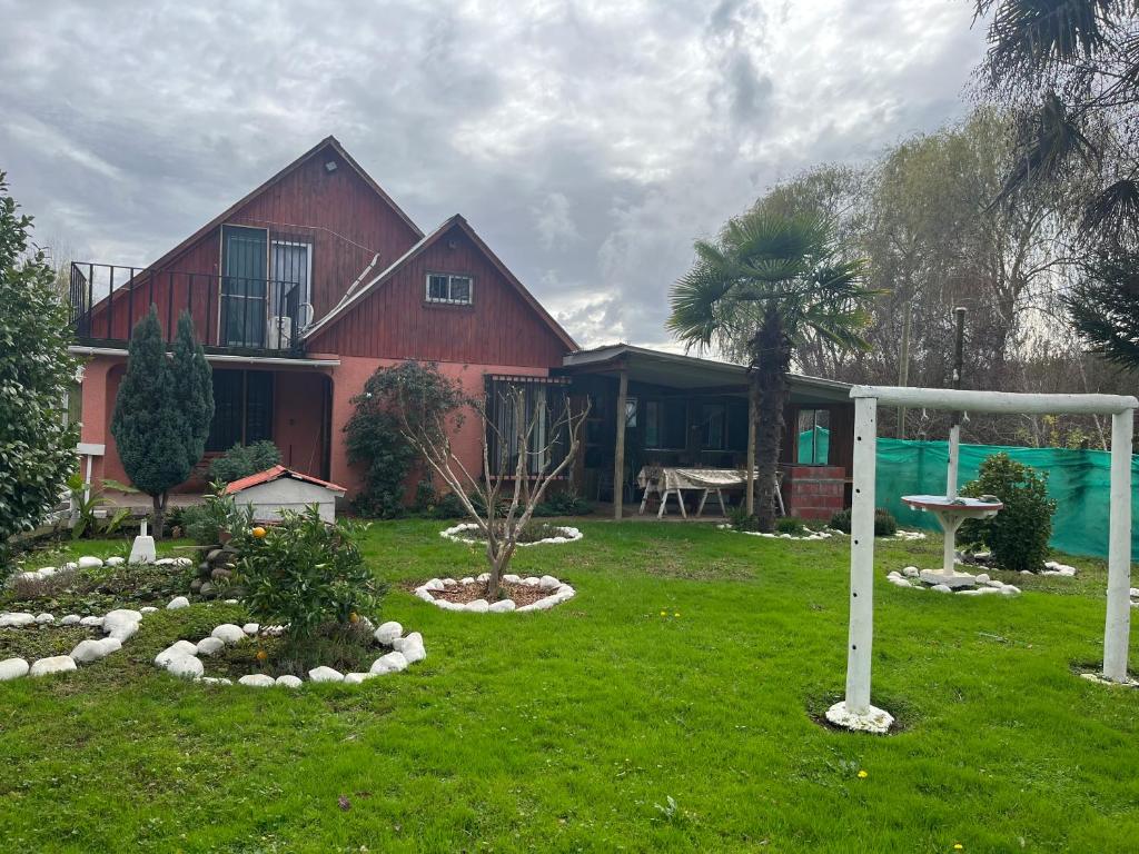 ein rotes Haus mit einem Garten mit einem Pavillon in der Unterkunft Alojamiento Machicura in Linares