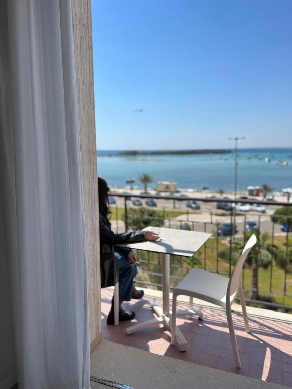 a person sitting at a table with a view of the ocean at Il Vascello in Porto Cesareo