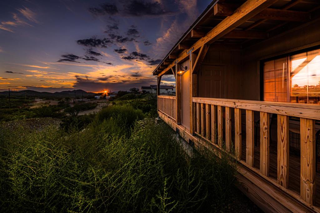 a house with a deck with a sunset in the background at Miners Cabin #4 - One Queen Bed - Private Balcony with Views in Tombstone