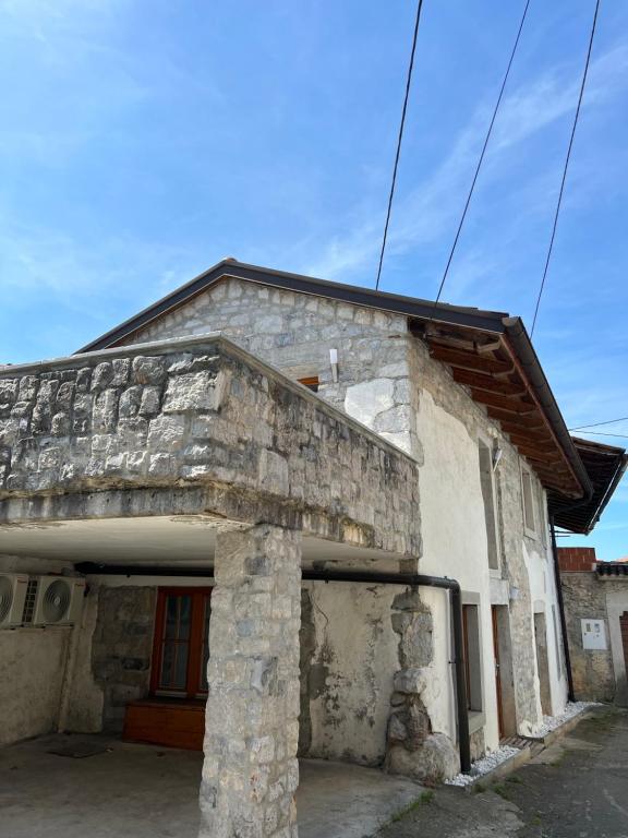 um antigo edifício de pedra com uma porta vermelha em Guesthouse 45 em Dutovlje