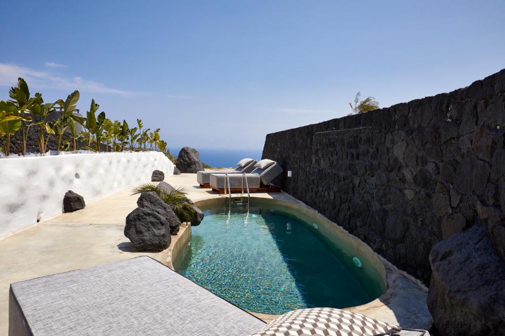 basen z patio i ścianą skalną w obiekcie Theano Cave Suites & Villas w Imerovíglion